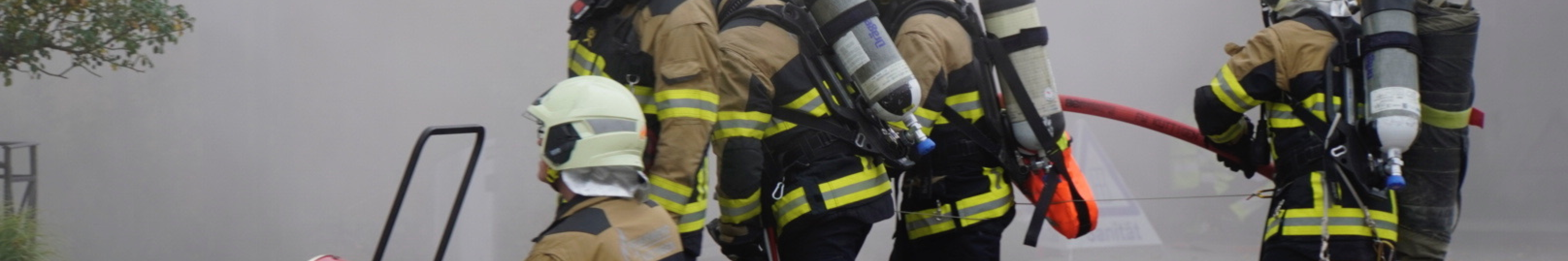 Ein Atemschutztrupp macht sich bereit, in das Brandobjekt zu gehen, welches bereits belüftet wird.